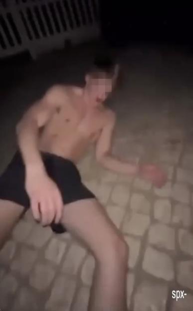 A young man lying on the ground, unconscious after being assaulted.