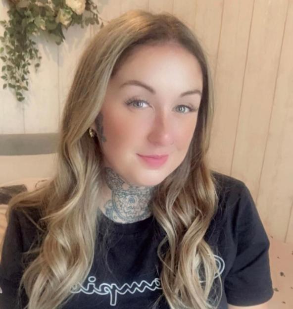 Woman with blonde hair and neck tattoo.
