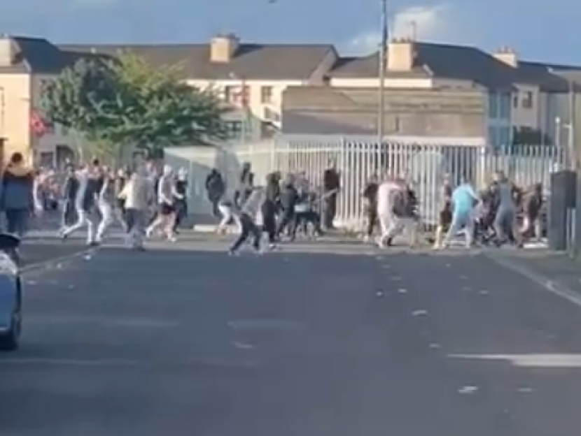 A large group of people fighting in a street.