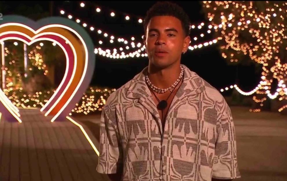 A man saying goodbye in front of a heart-shaped light installation.