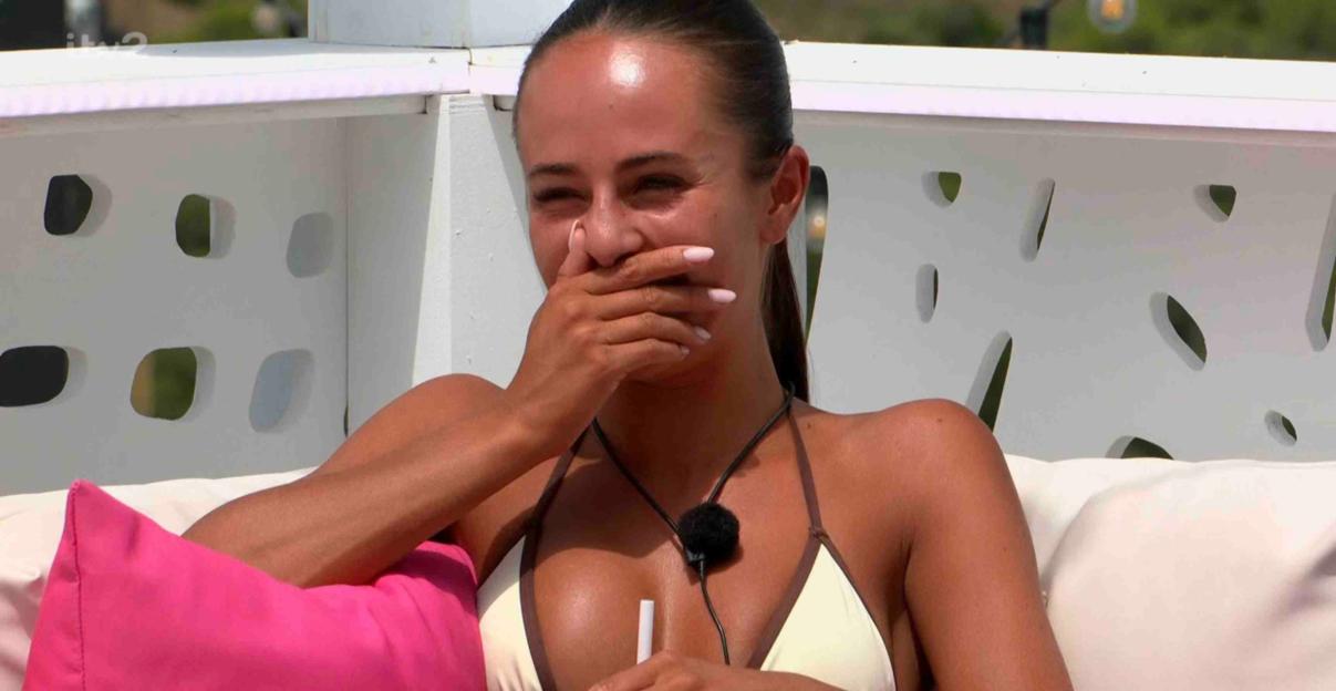 Woman laughing and covering her mouth with her hands.