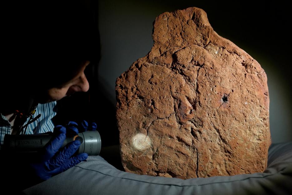 A curator examines a 4,000-year-old Egyptian handprint on a soul house.