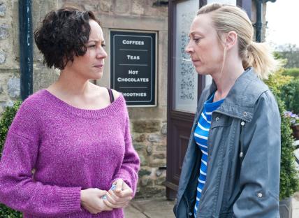 Two women talking outside a cafe.