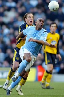 Manchester City's Trevor Sinclair dribbling past Wigan's Reto Zeigler during an FA Cup match.
