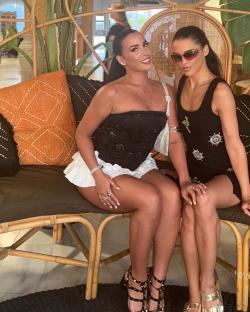 Two women sitting together on a bench.