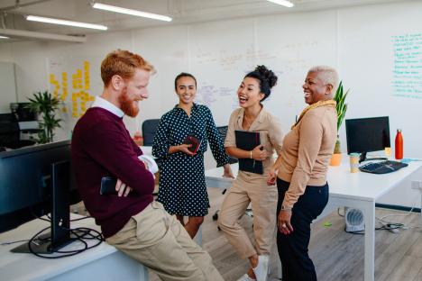 Four colleagues laughing together in a London office.