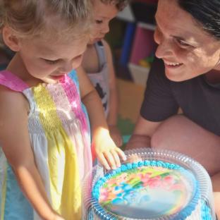 Girl looking at a decorated cake with a woman and another child.
