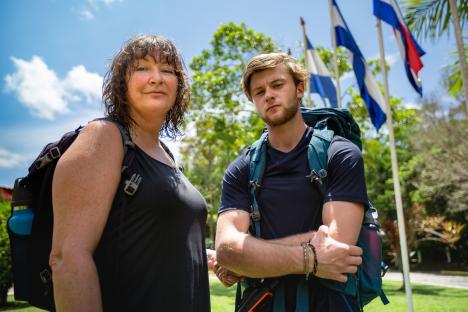 Photo of a mother and son with backpacks, standing outdoors.