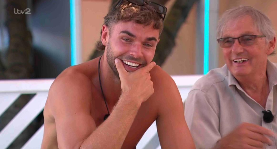 Screenshot of a man smiling and an older man smiling next to him.
