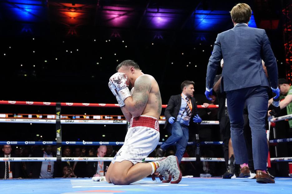 A boxer kneeling in the ring after being knocked down.