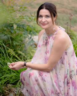 Woman in floral dress kneeling in a garden.