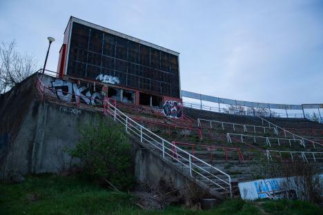 Abandoned stadium with graffiti and damaged scoreboard.