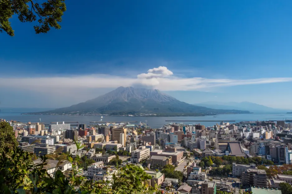 Aerial view of a city with a volcano in the background.