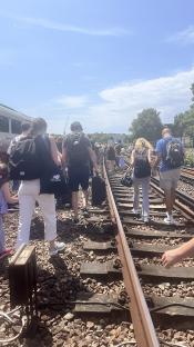Passengers walking along train tracks after a train breakdown.