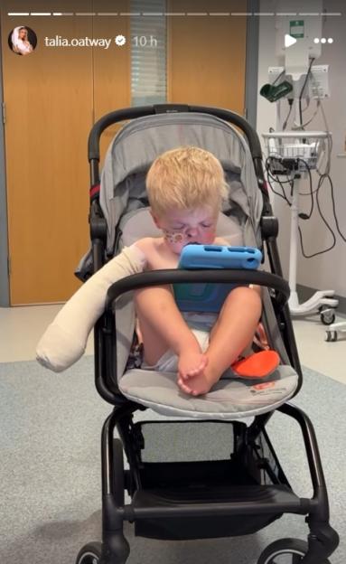 Young boy with arm injury in stroller using tablet.