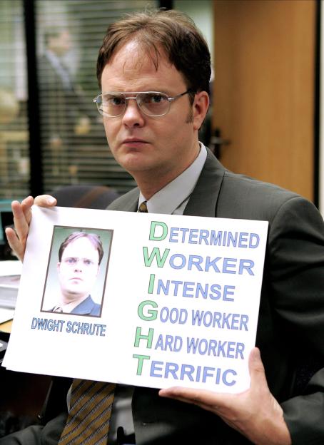 Dwight Schrute from The Office holding a sign describing himself with the word