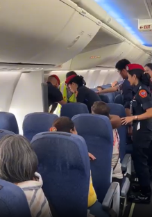 Medical personnel assisting a passenger on an airplane.