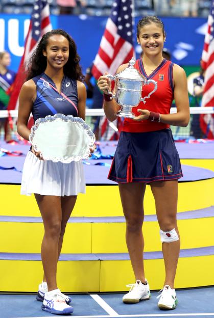 Leylah Fernandez and Emma Raducanu at the US Open, holding their respective trophies.