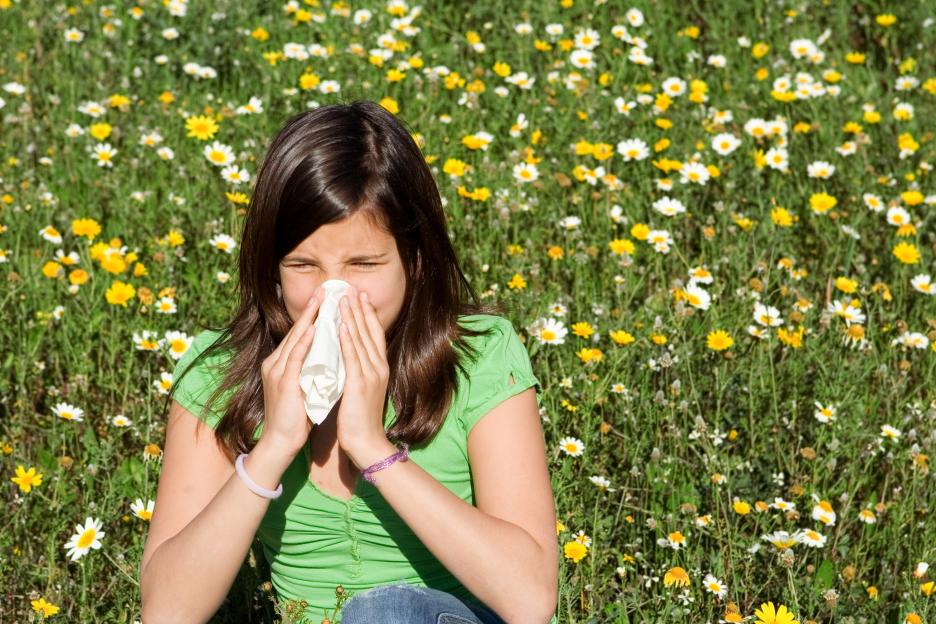 Girl blowing her nose in a flower field.
