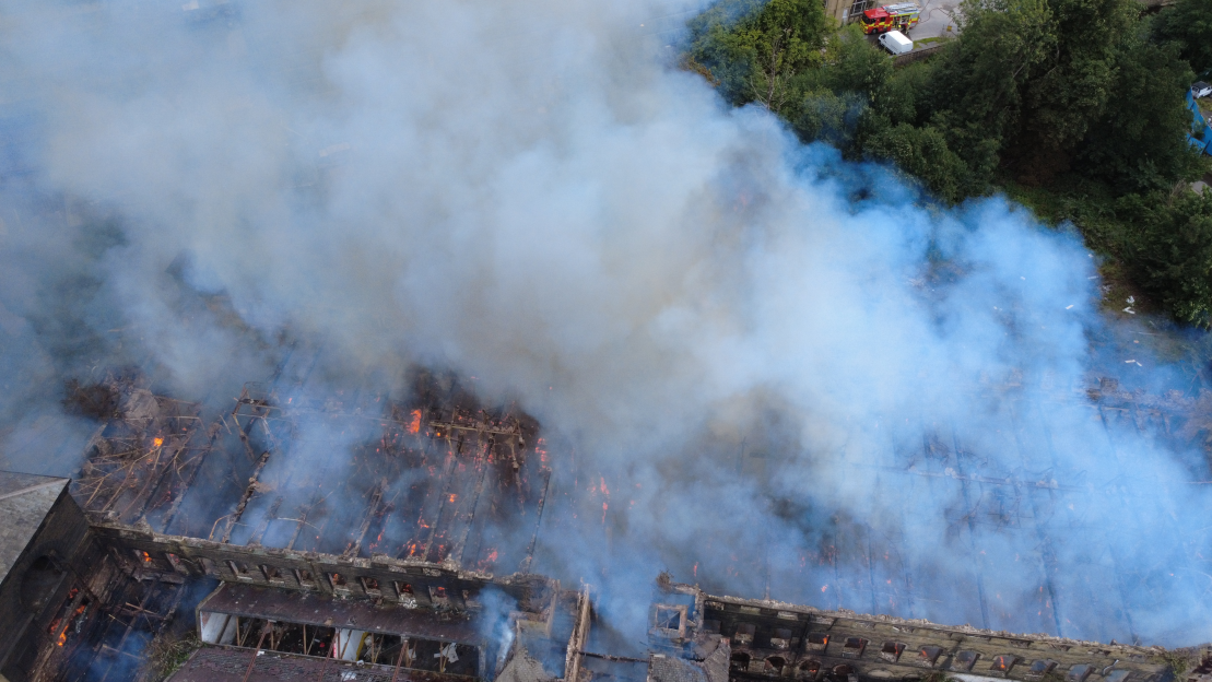 Aerial view of a building engulfed in fire and smoke.