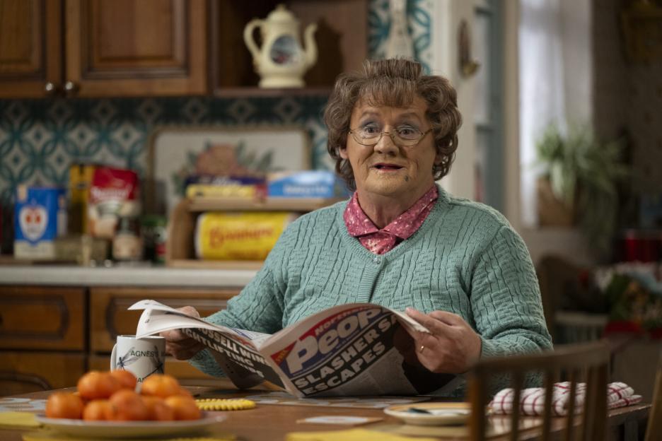 Agnes Brown reading a newspaper at her kitchen table.