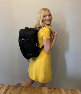 Woman in yellow dress wearing a black backpack.