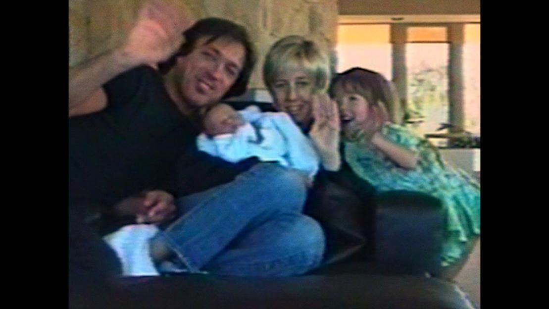 Family with a baby and a young child sitting on a couch.