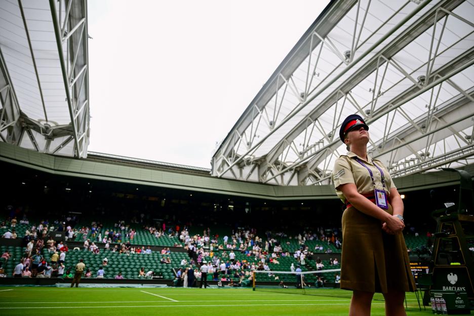 A security guard stands on Centre Court at Wimbledon with the roof open.