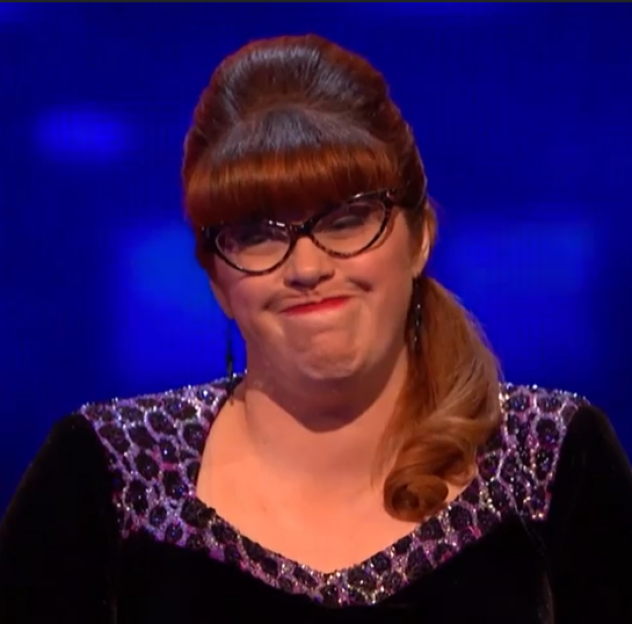 Screenshot of a woman with red hair and glasses making a skeptical face.