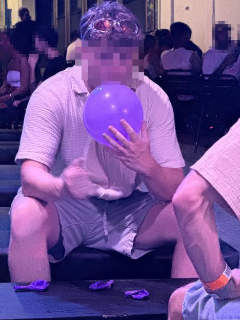 Person inflating a purple balloon.