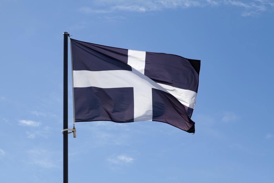 Saint Piran's Flag waving against a blue sky.