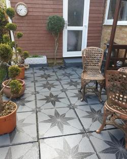 Patio with star-patterned gray paint and metal chairs.