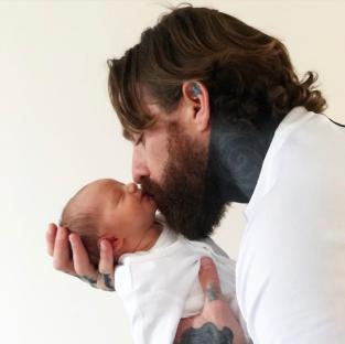 A father kissing his newborn baby.