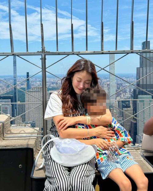 Woman hugging child on skyscraper observation deck.