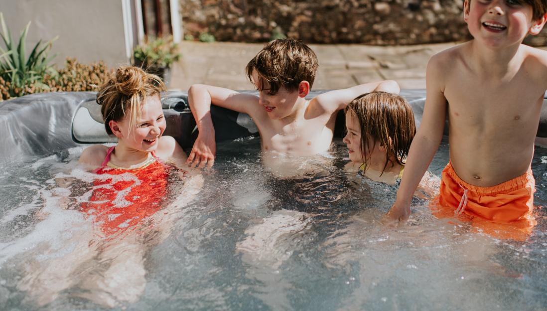 Four children splashing in a hot tub.