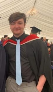 A young man in a graduation gown.