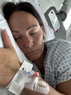 Woman sleeping in a hospital bed with an IV line.