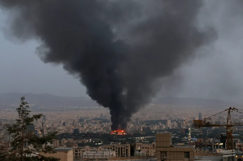 Large plume of black smoke rising over a city.