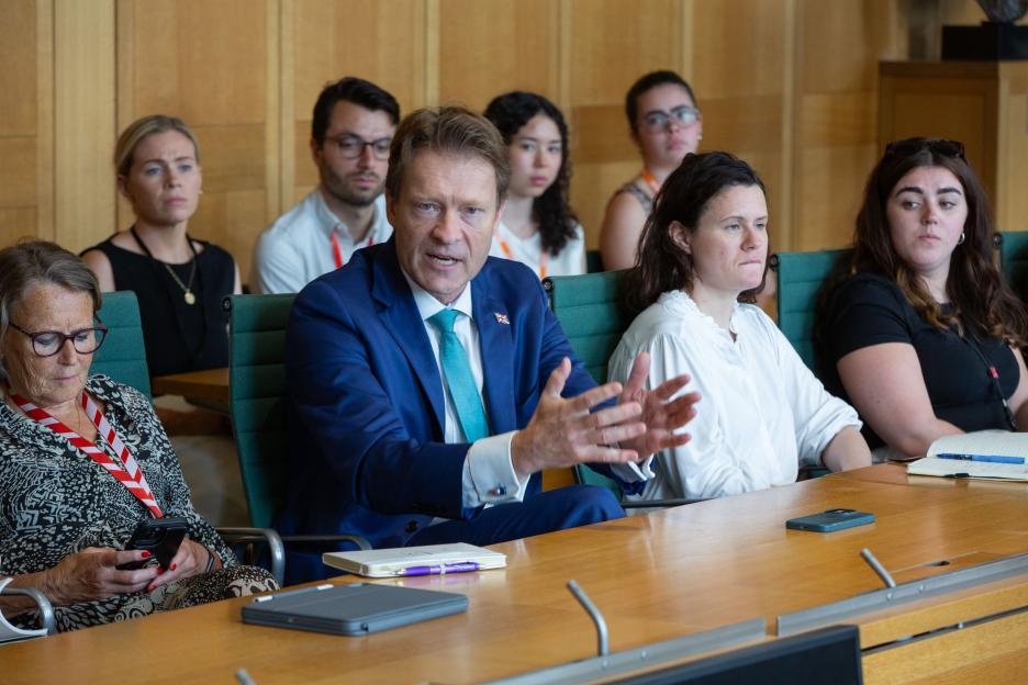 A man in a suit speaks at a parliamentary screening.