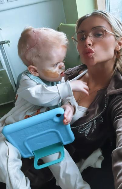 A woman holding her young son in a hospital room.