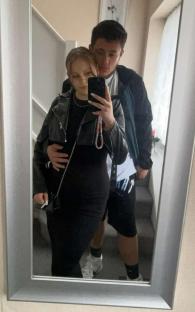 Mirror reflection of a pregnant couple taking a selfie.