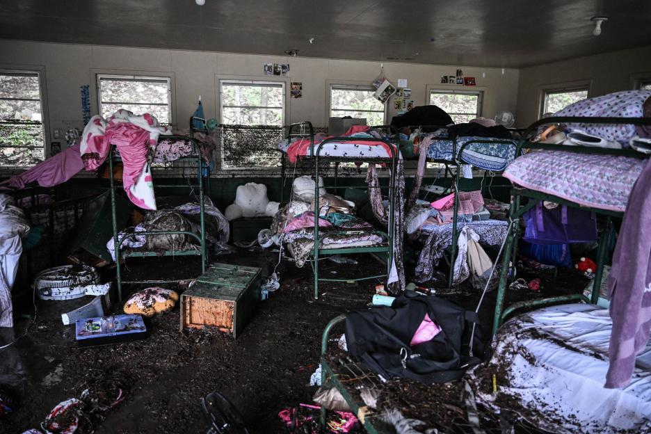 Muddy bunk beds and belongings in a flood-damaged cabin.