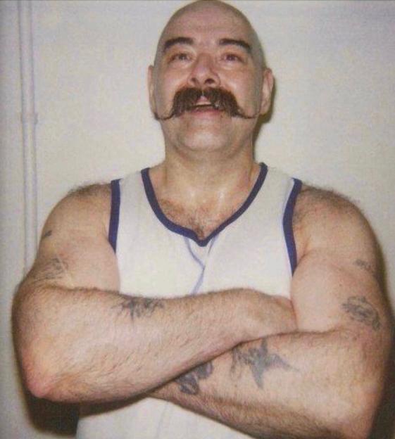 Charlie Bronson, a notorious prisoner, with arms crossed.