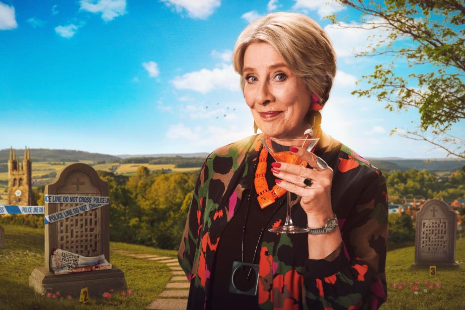 Phyllis Logan as Cora Felton holding a martini glass in a graveyard.