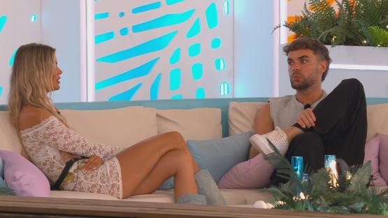 Helena and Harry from Love Island sitting on a couch and talking.