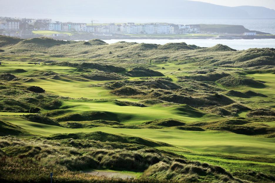 View of a golf course with the town of Portrush in the background.