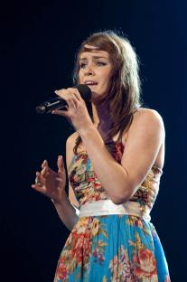 A woman singing into a microphone on a stage.