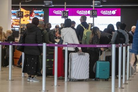 Passengers at an Edinburgh Airport Qatar Airways check-in desk after a flight cancellation.
