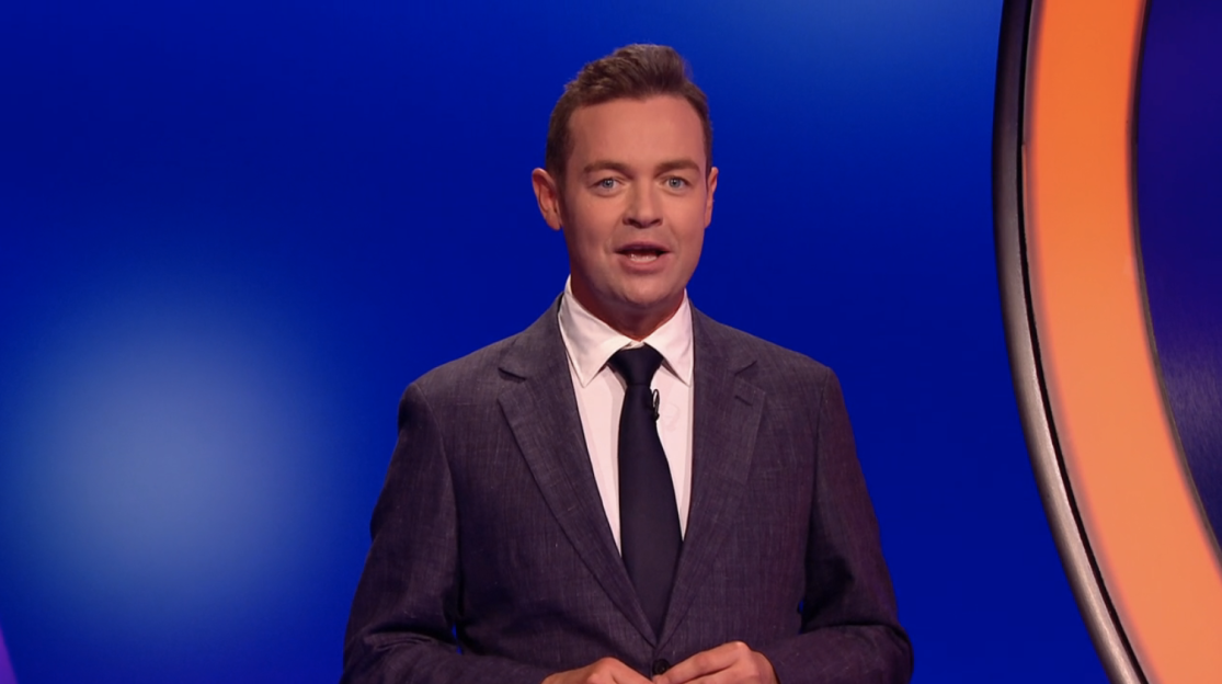 Screenshot of a man in a suit speaking.