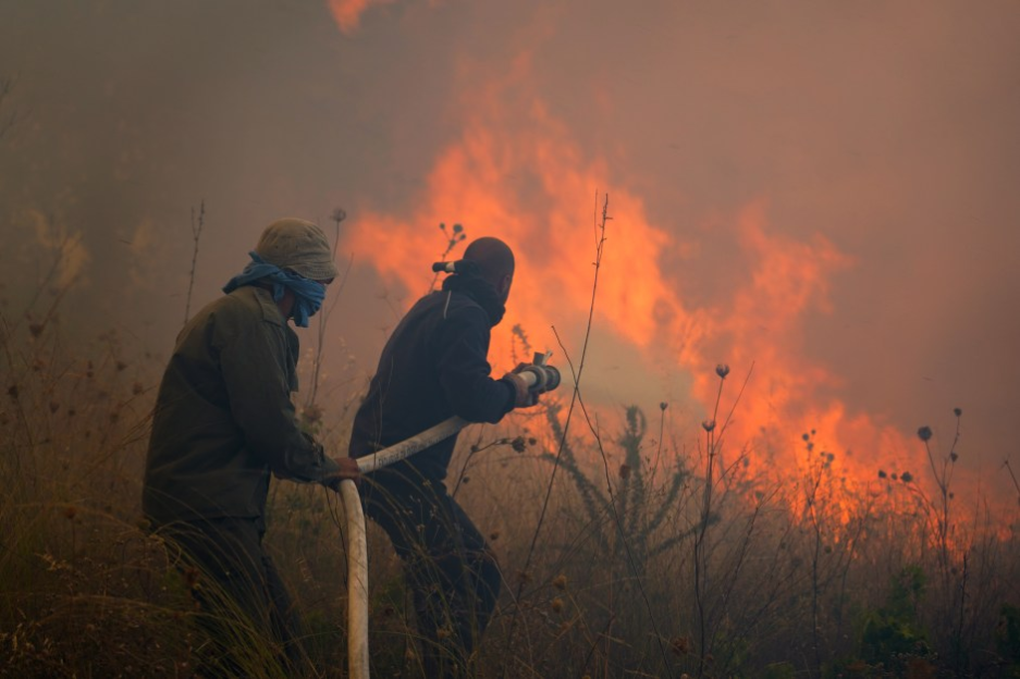 Two firefighters battling a wildfire.